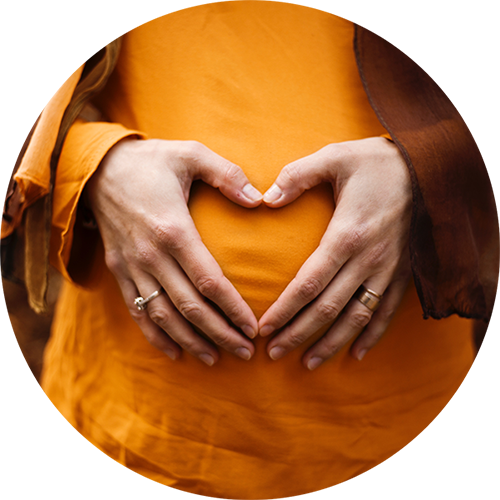 Woman making a heart with her hands on pregnant tummy